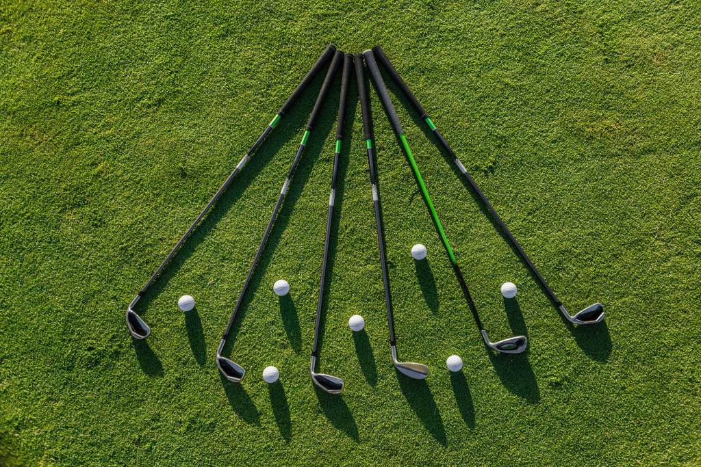 Golf clubs and balls arranged on grass demonstrating a golf practice setup