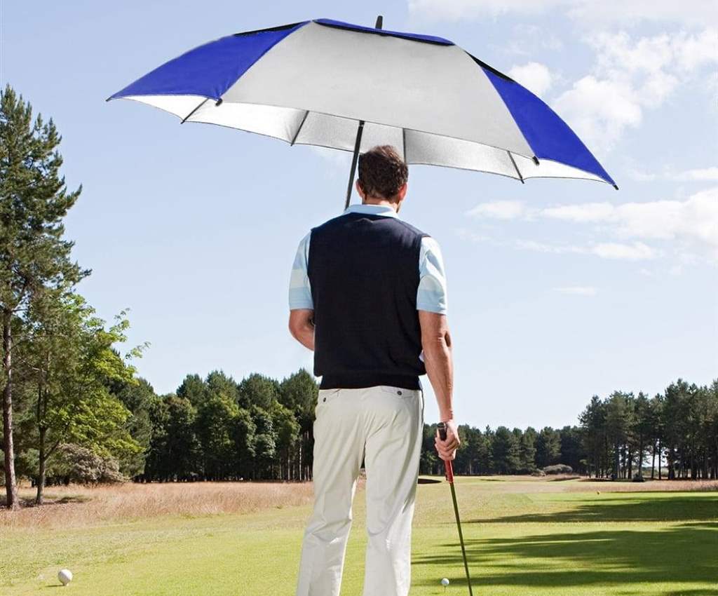 Golfer using large umbrella in heavy rain on course