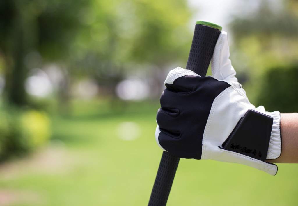 Golfer wearing glove holding club with strong grip
