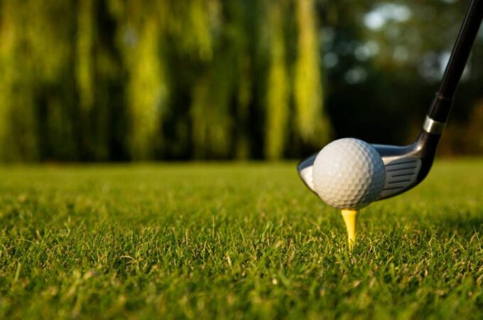 Mid handicap golfer hitting iron shot with golf balls on green grass