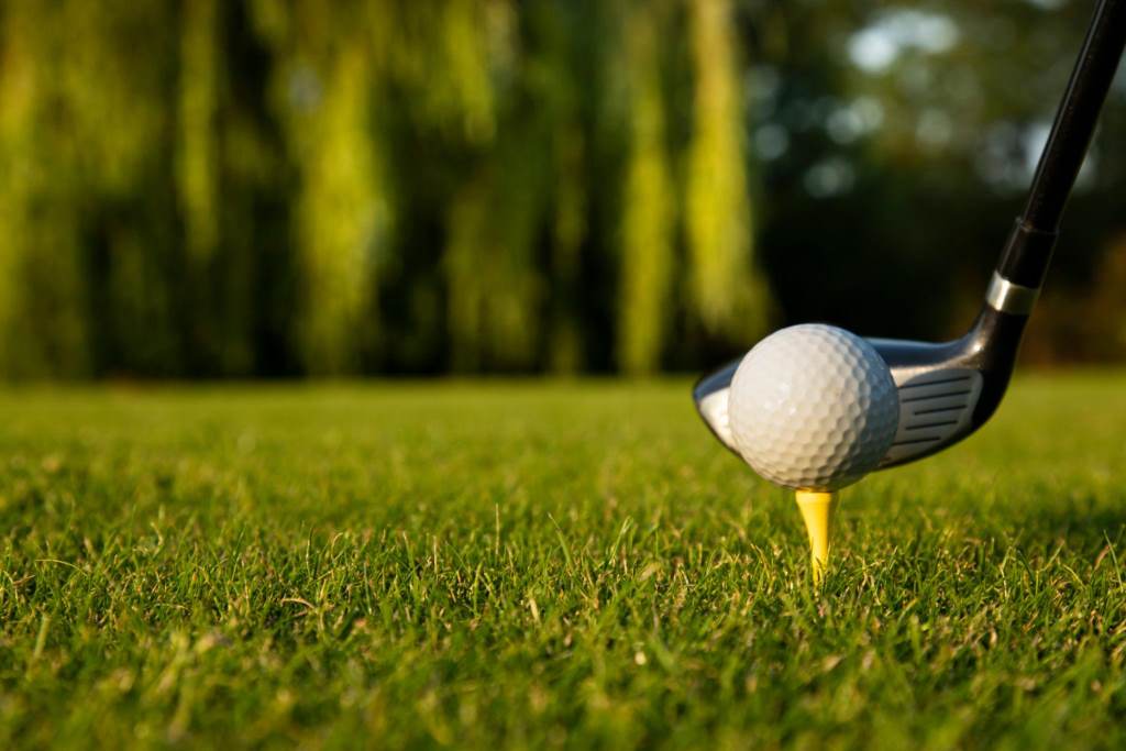 Mid handicap golfer hitting iron shot with golf balls on green grass