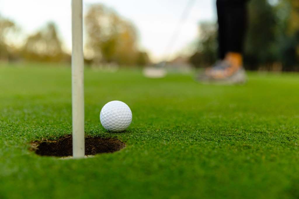 the hole on the golf course as the golfer hits the ball