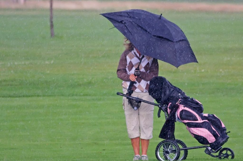 Golfer wearing waterproof rain gear playing in wet conditions on a golf course